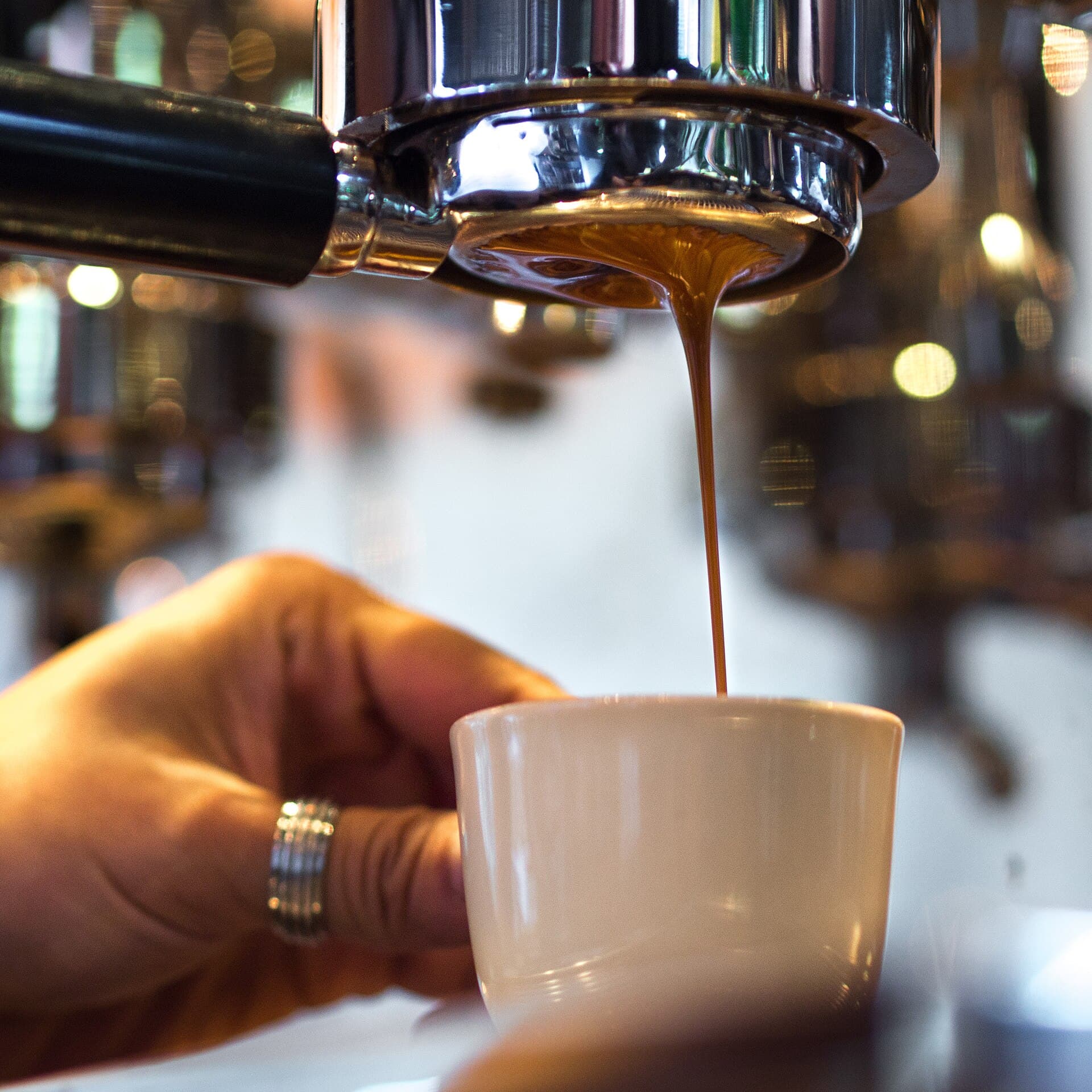 Professional espresso extraction with naked portafilter showing golden crema